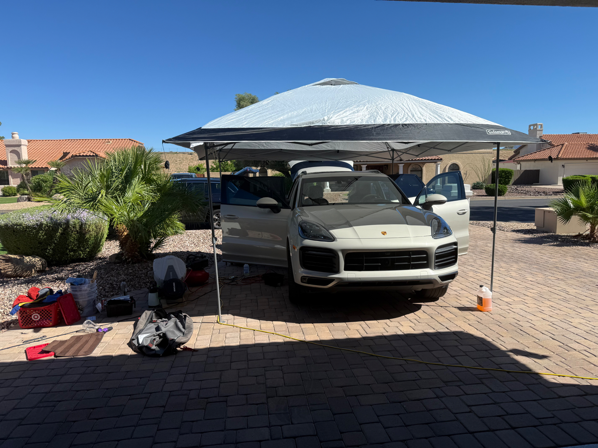 White Porsche Cayenne under a canopy during a mobile detail
