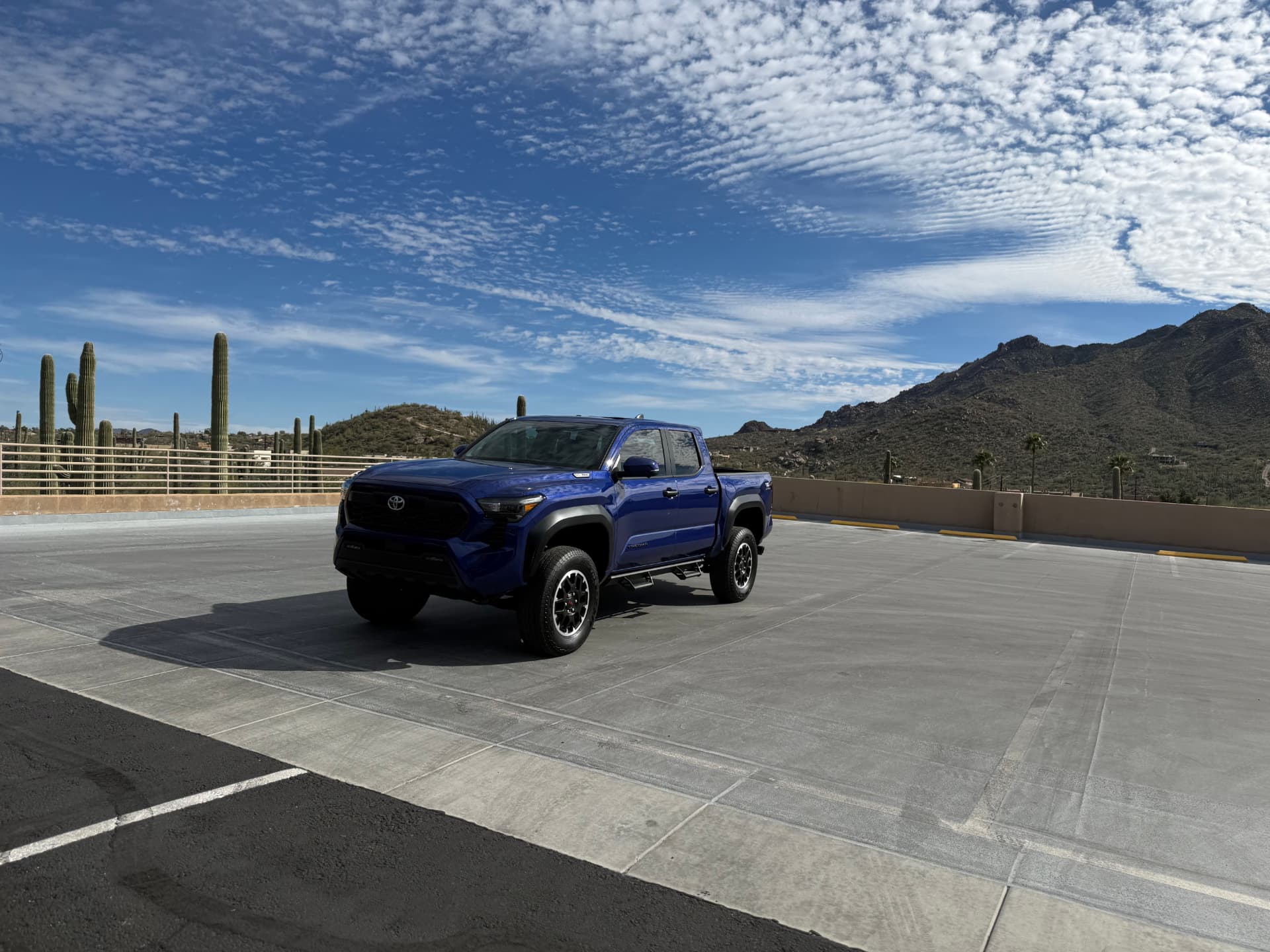 Detailed blue Toyota Tacoma parked with desert mountains behind it