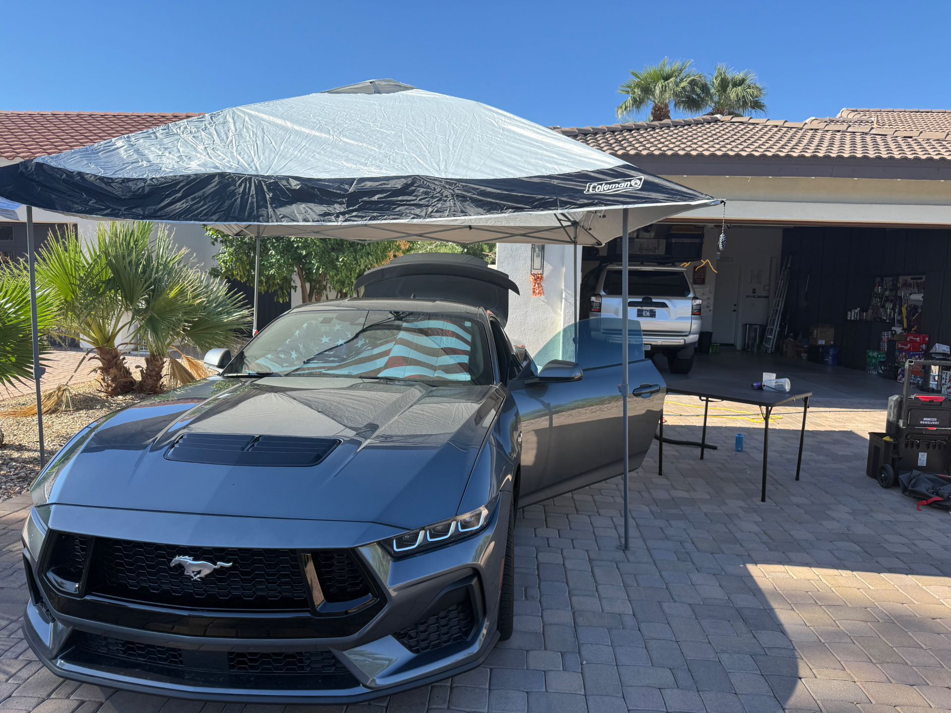 Gray Ford Mustang GT under a canopy during a mobile detail with the door open