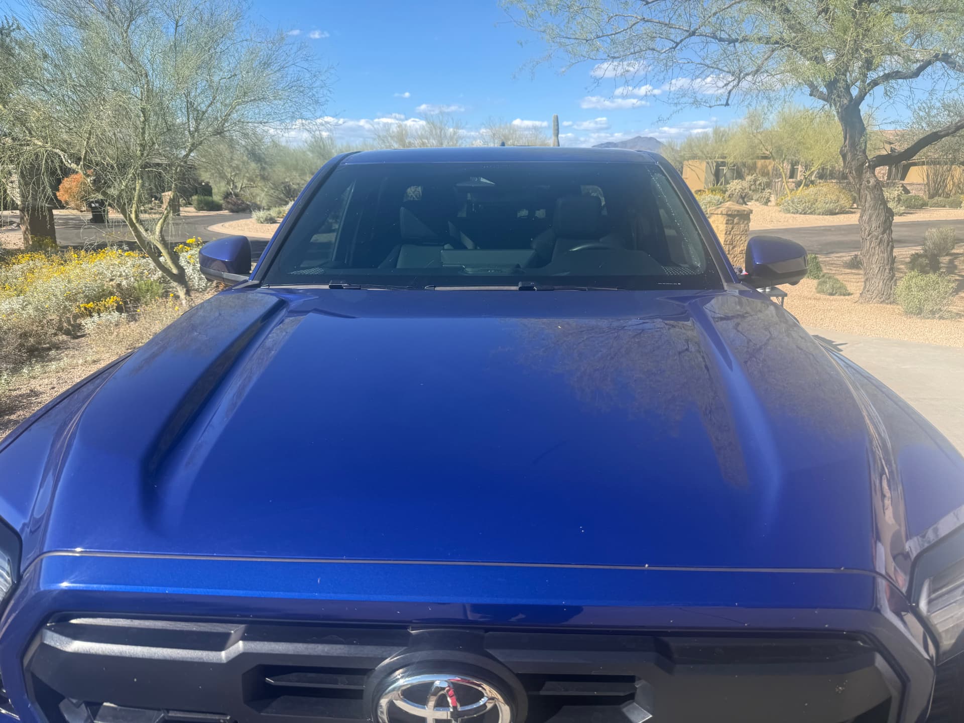 Overhead view of the polished hood of a blue Toyota Tacoma