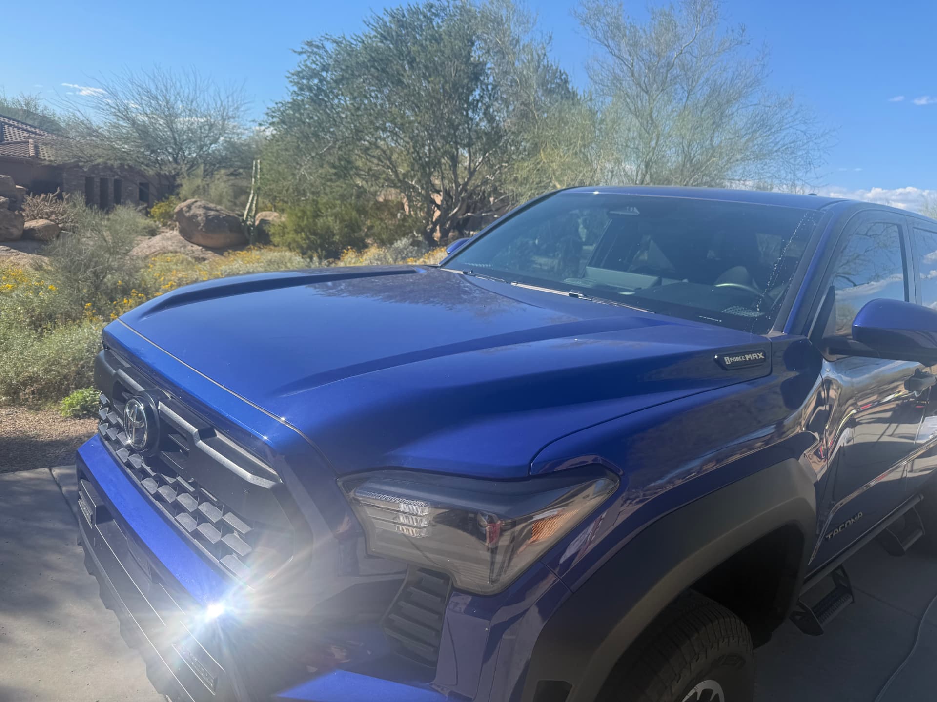 Gloss reflection across the hood of a blue Toyota Tacoma
